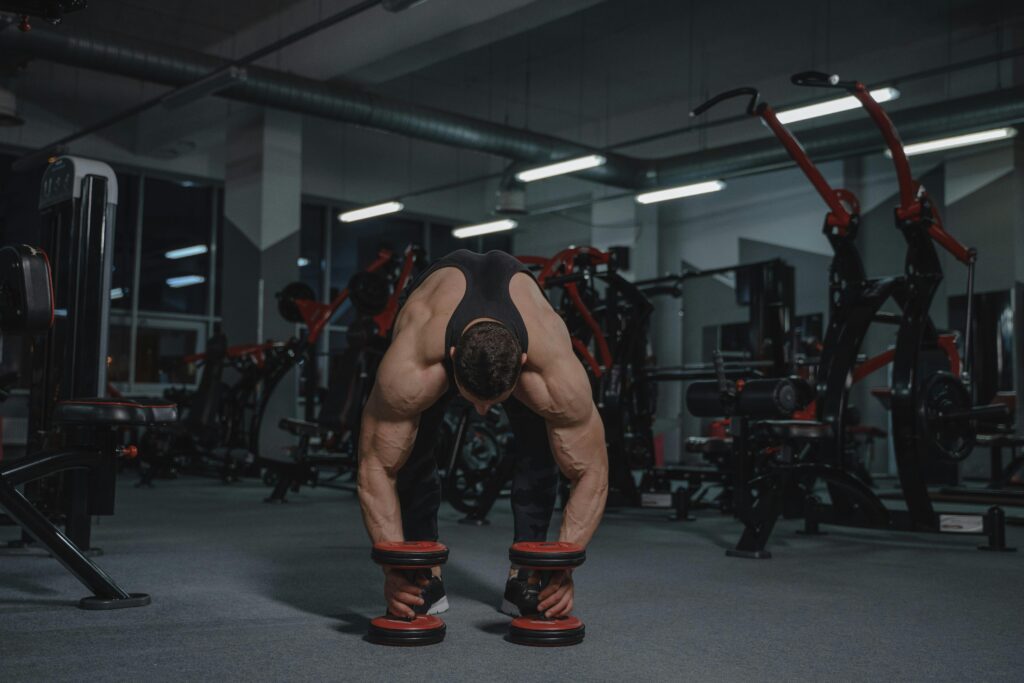 Muscular man in a gym lifting heavy dumbbells showcasing strength and fitness.